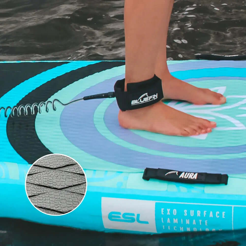 Persona de pie en una tabla de paddle inflable azul con correa y almohadilla de cubierta texturizada