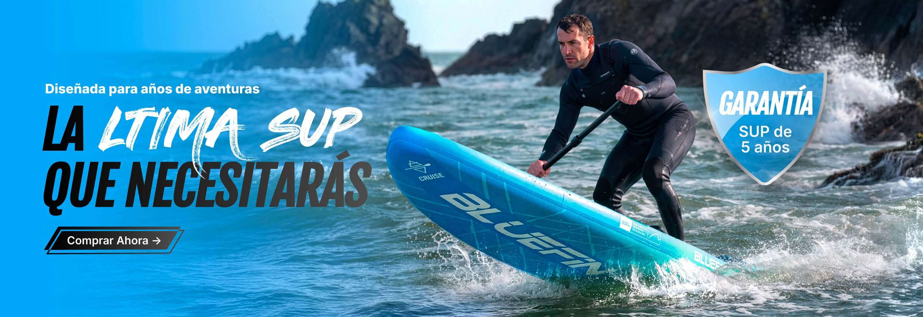 Man paddling a blue inflatable stand-up paddleboard on water near rocky shore