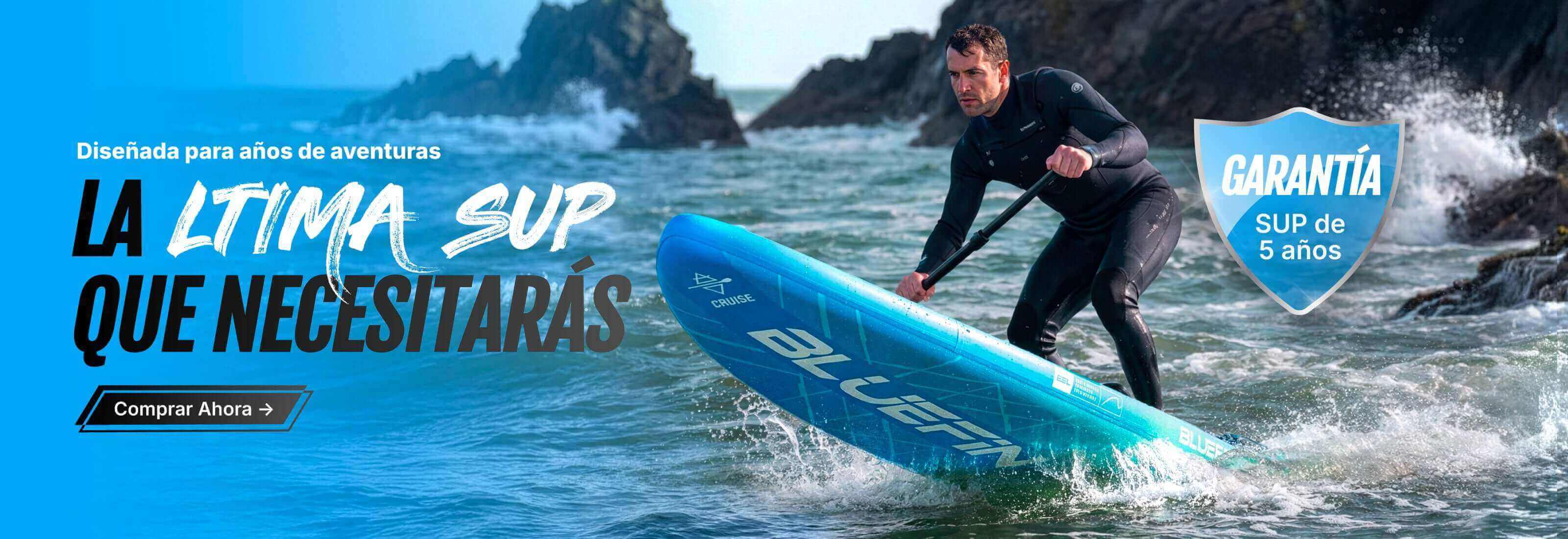 Man paddling a blue inflatable stand-up paddleboard on water near rocky shore