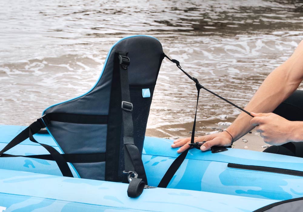 Close-up of a blue inflatable paddleboard seat being adjusted by a person near water