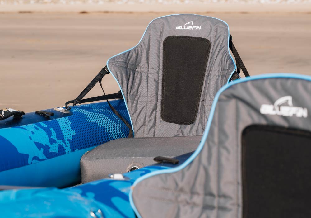 Close-up of a Bluefin kayak seat with gray fabric, back support, and blue accents on the kayak.