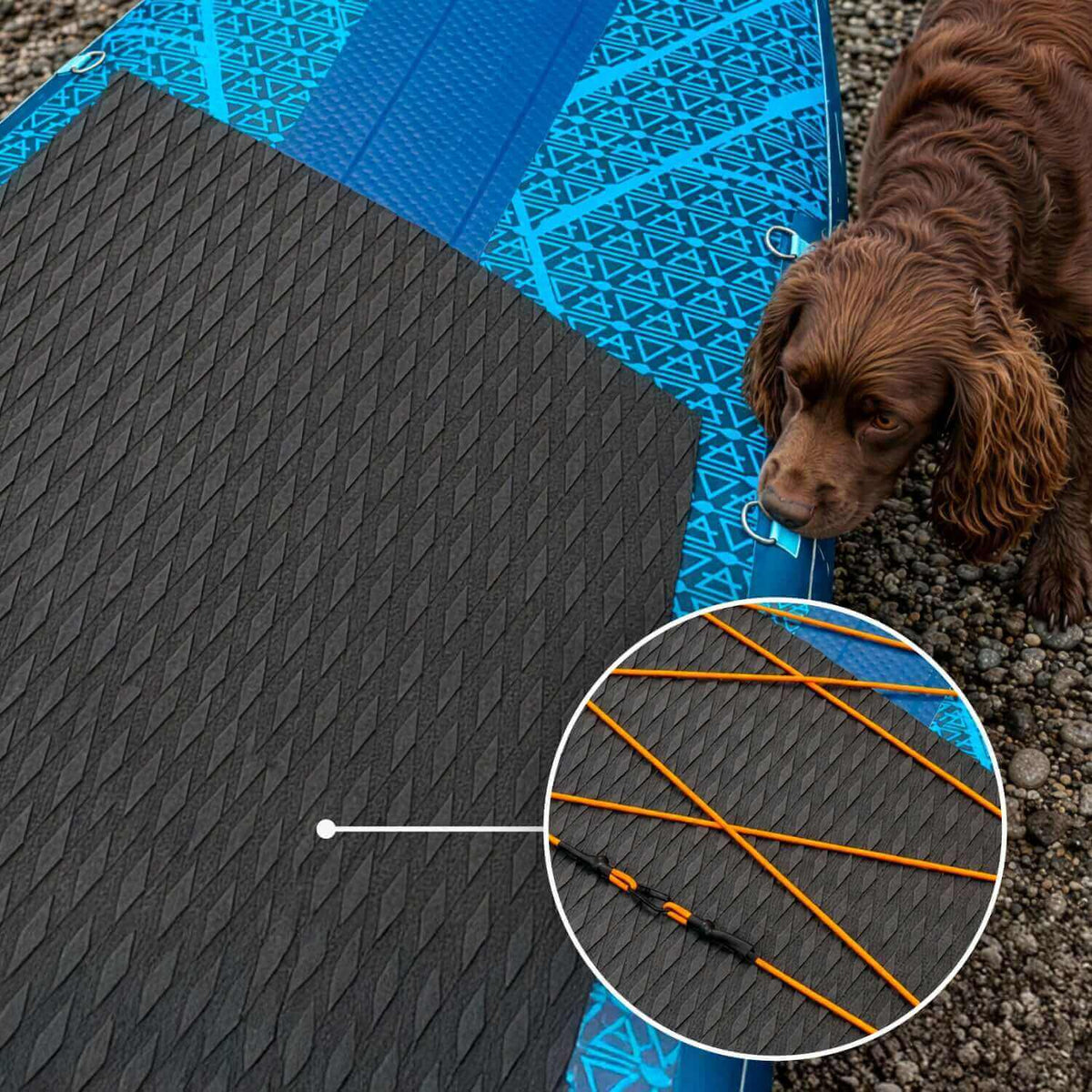 Paddleboard hinchable con superficie antideslizante negra texturizada, cuerdas elásticas naranjas y un perro marrón cerca