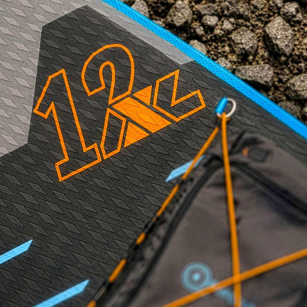 Primer plano de la cubierta texturizada de una tabla de paddle surf con el número 12 y detalles naranjas