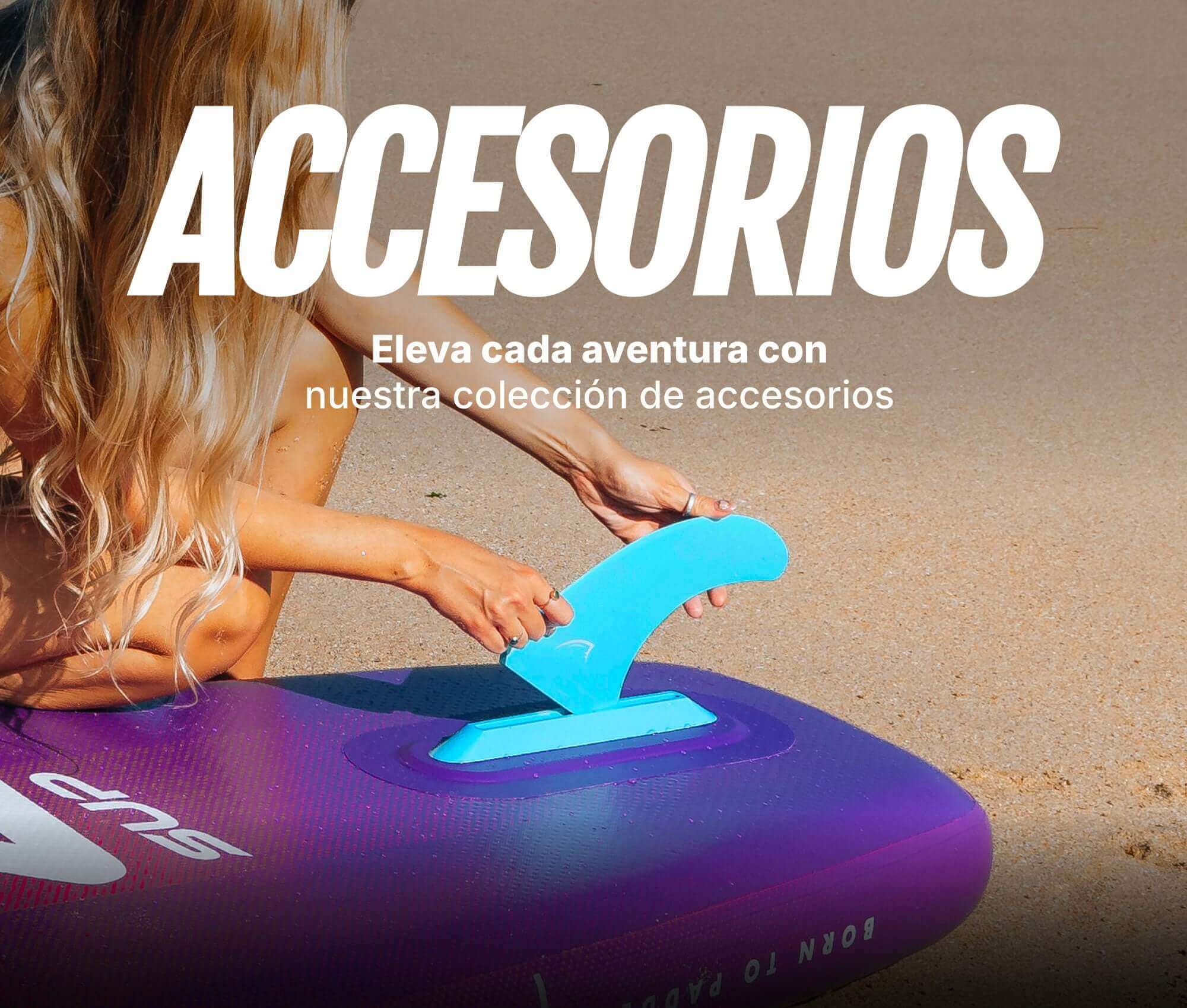 Person attaching a blue fin to a purple inflatable paddleboard on a sandy beach