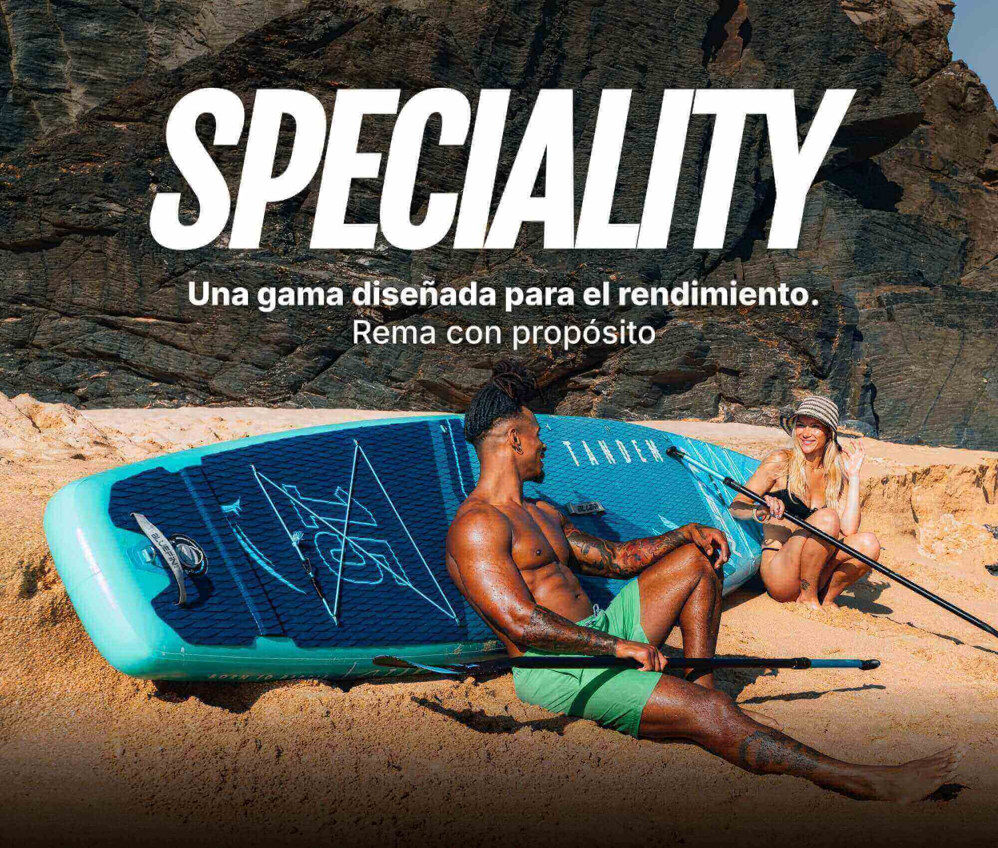 Two people relaxing on a blue inflatable paddleboard on the beach, with paddles nearby.