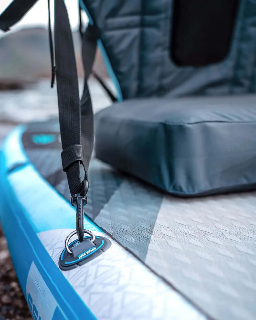 Close-up of a blue inflatable paddleboard with a black seat and attachment strap.
