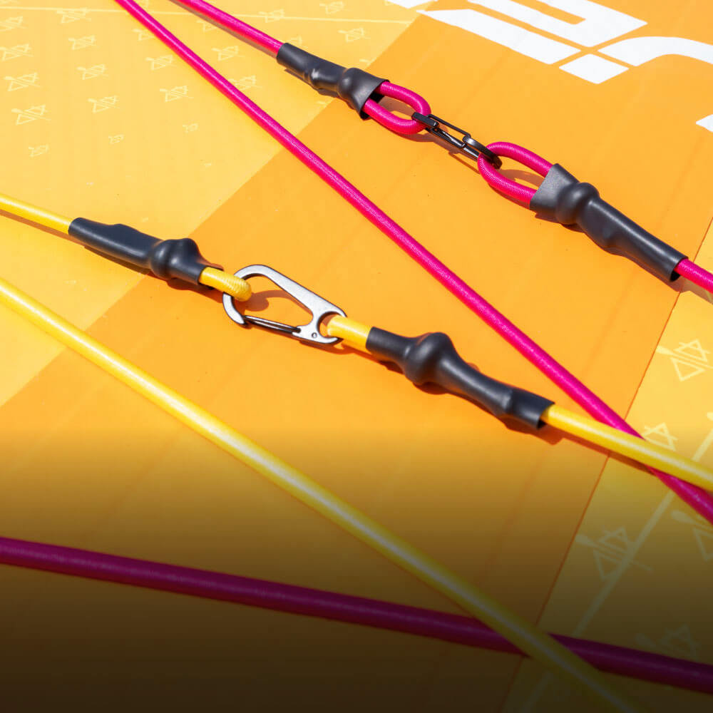 Colorful pink and yellow lines with clips on an orange surface, likely part of a paddleboard setup.