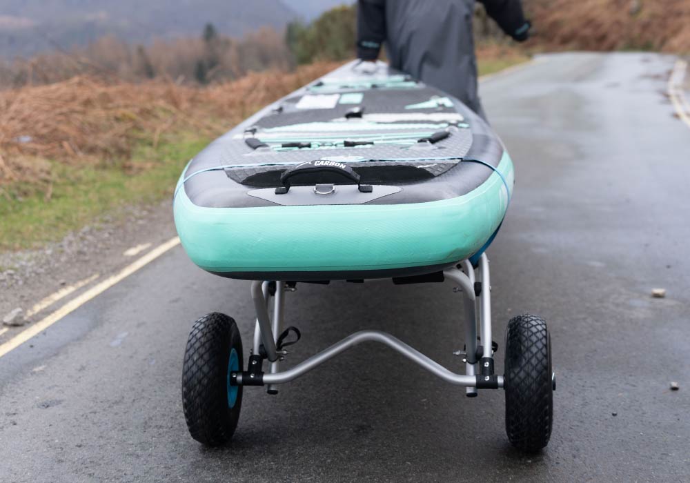 Inflatable paddleboard with a turquoise bottom, wheels, and textured deck pad for easy transport