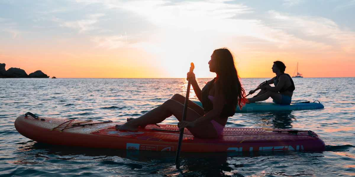 two people paddleboarding at sunset 