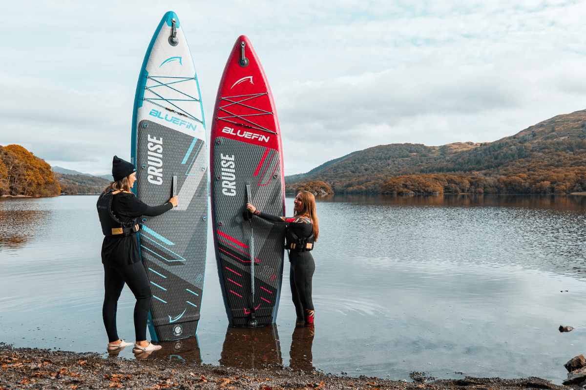 two people stood holding their paddleboards by the lake
