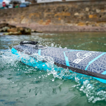 Tabla de paddle inflable con superficie texturizada, acentos azules y agua salpicando a su alrededor